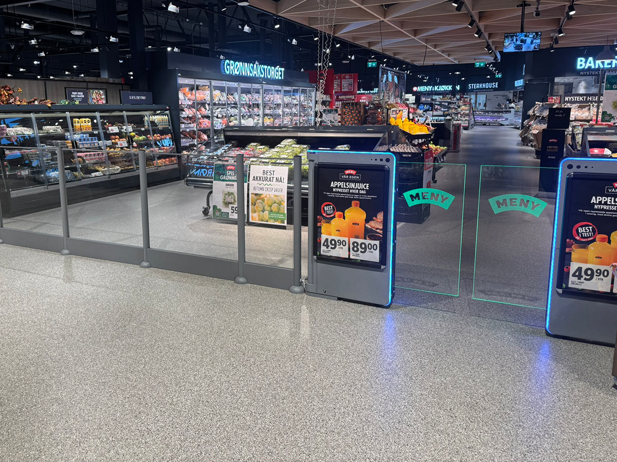 innendørs inngang til en Meny butikk med små skyvedører i glass til høyre.