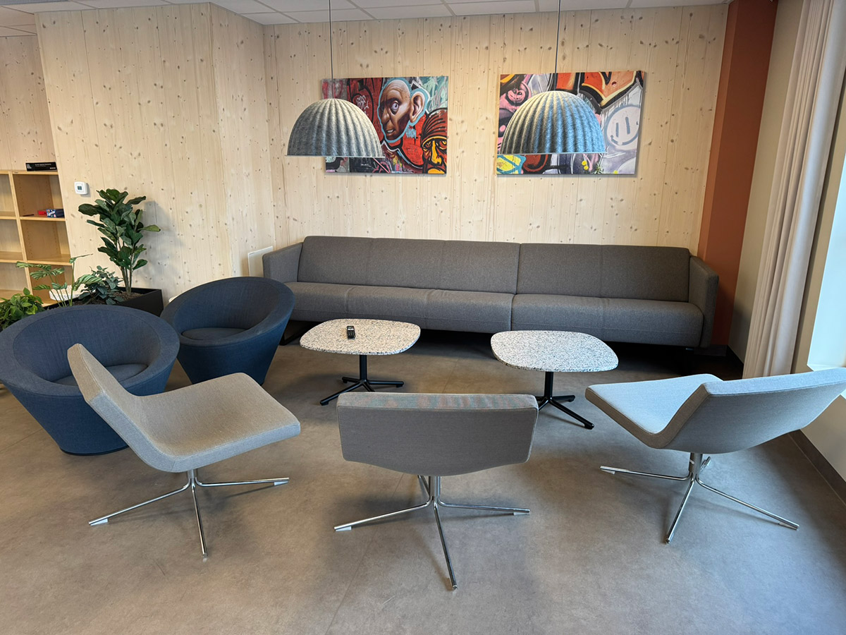 Sosial sone med sofaer, lenestoler, bord og kunst på veggene i Lund Torv studentboliger.