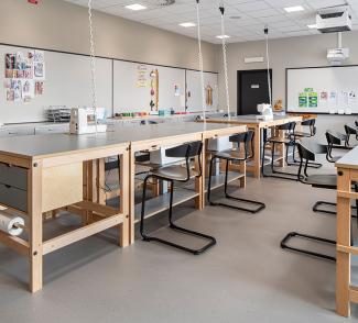klasserom på skolen med arbeidsbenker og stoler. Symaskin stående oppå arbeidsbenken