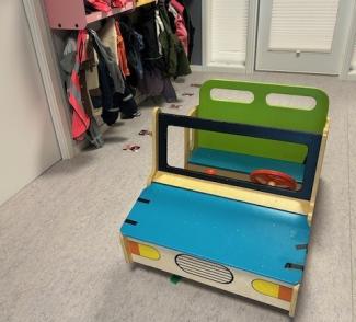 en lekebil i sterke farger stående på gulvet i gangen i en barnehage