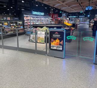 innendørs inngang til en Meny butikk med små skyvedører i glass til høyre.