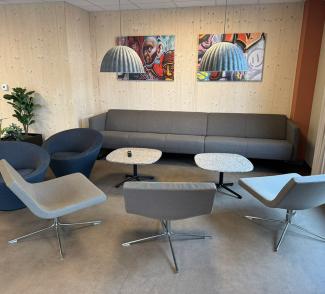 Sosial sone med sofaer, lenestoler, bord og kunst på veggene i Lund Torv studentboliger.