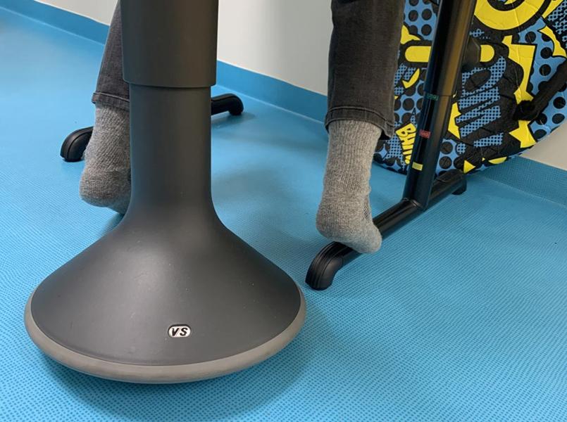 nærbilde av føttene til et barn som vipper på krakken på et blått gulv