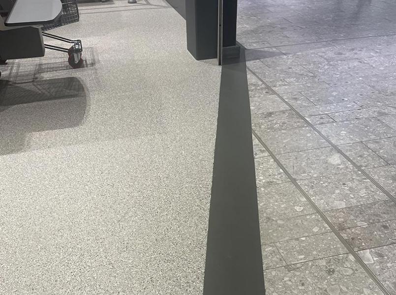 nærbilde av gulvet i overgangen mellom en meny butikk og fellesområde