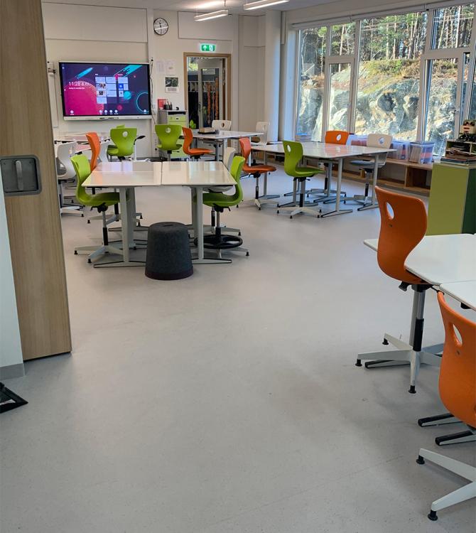 klasserom med fargerike stoler i grønt og orange, og et grått gulv