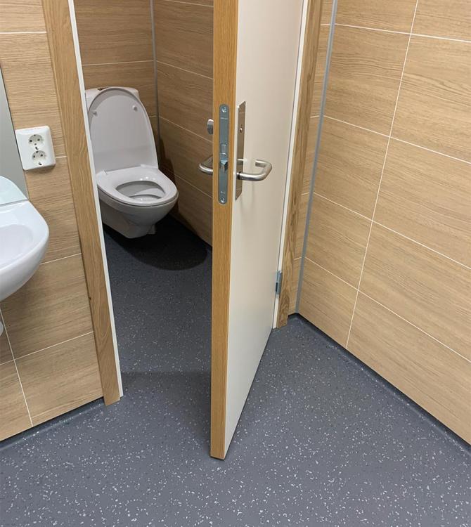 bilde av et toalett med døren åpen, som viser samme gulv i hele rommet