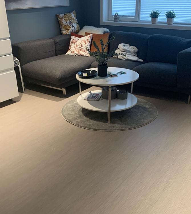 Bilde av en stue på Vennesla Omsorgssenter med en mørk sofa i hjørnet