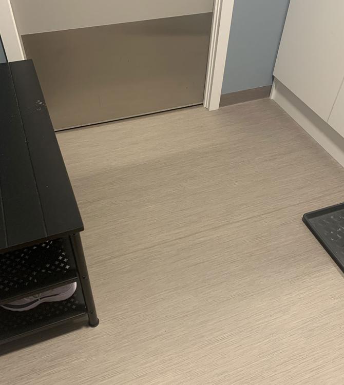 nærbilde av et gulv i en gang, hvor man også ser overgangen til gulvet i fellesområdet