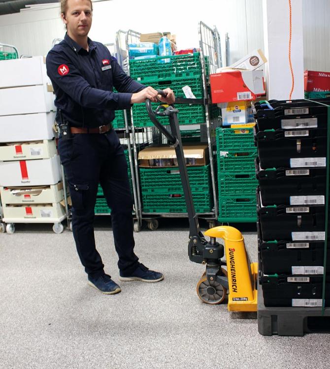 bilde av en ansatt hos meny som kjører jekketralle på lageret