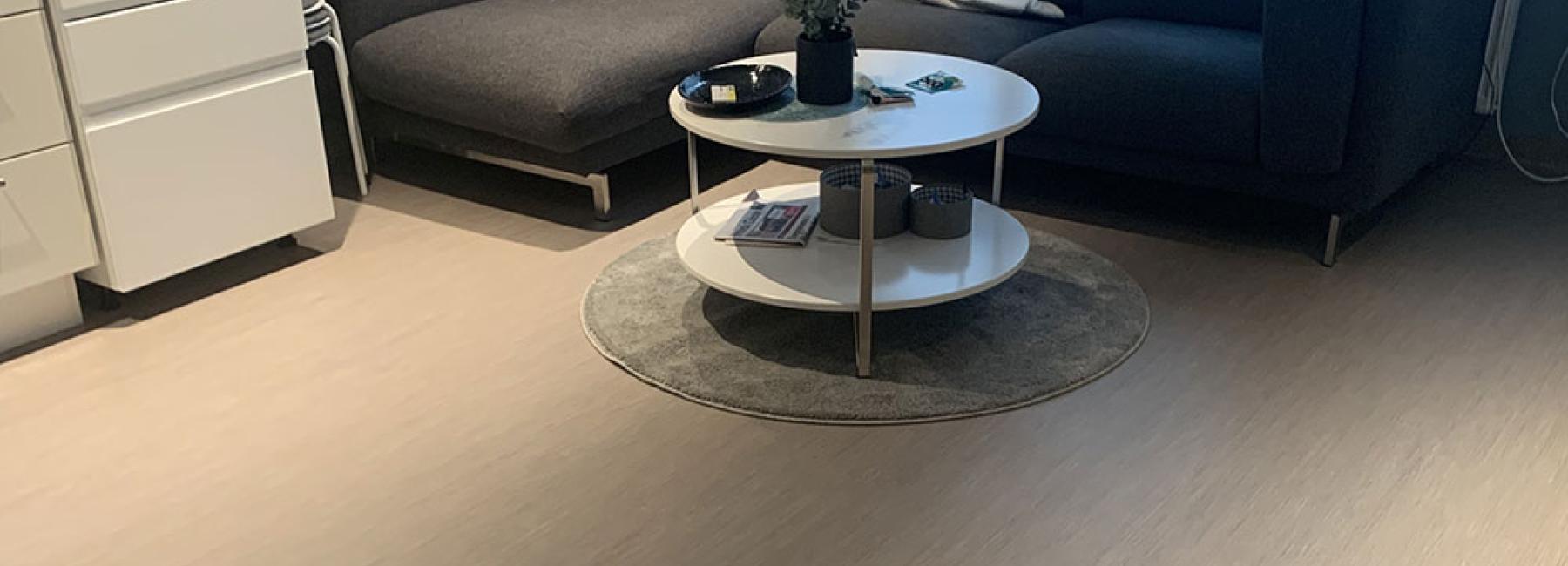 Bilde av en stue på Vennesla Omsorgssenter med en mørk sofa i hjørnet