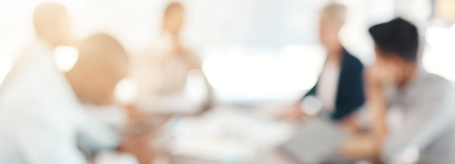 et blurry bilde av et salgsteam som sitter dunt et bord