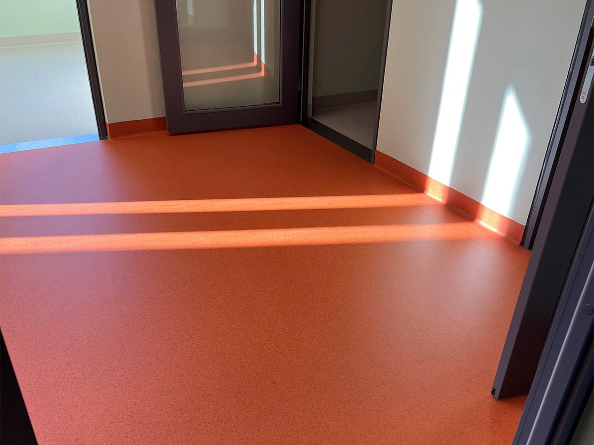 Nærbilde av et rødt gulv i fellesareal på Nye Narvik Sykehus