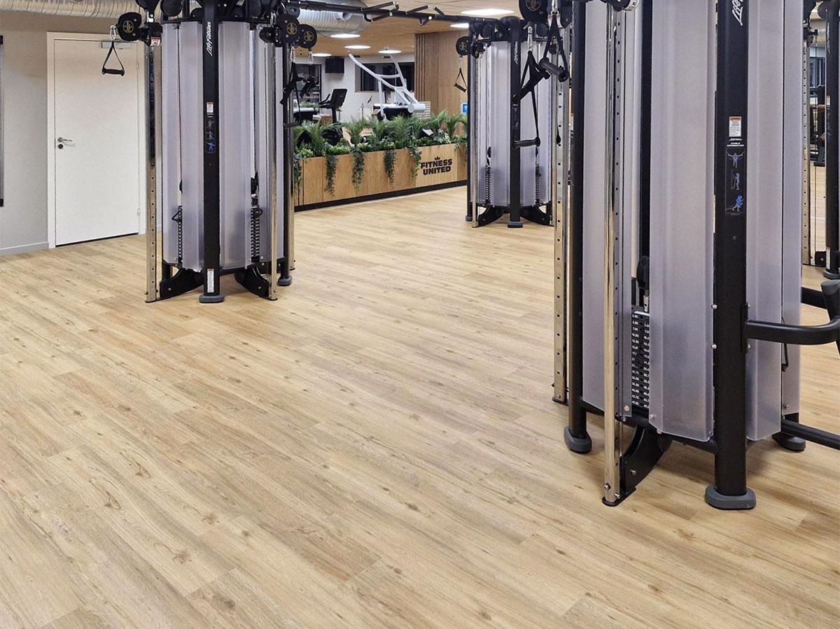 Bilde av nytt gulv i et treningssenter, med treningsapparater i bakgrunnen