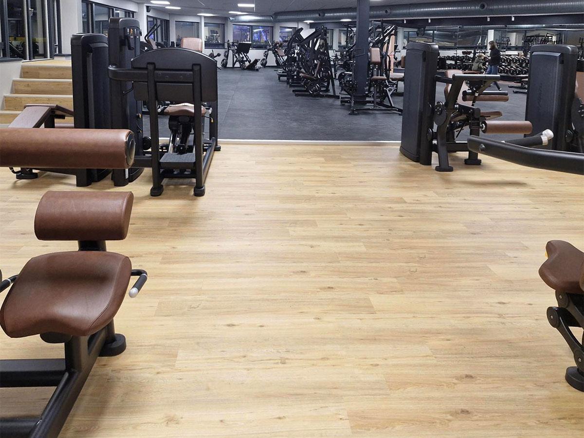 Bilde av nytt gulv i et treningssenter, med treningsapparater i bakgrunnen
