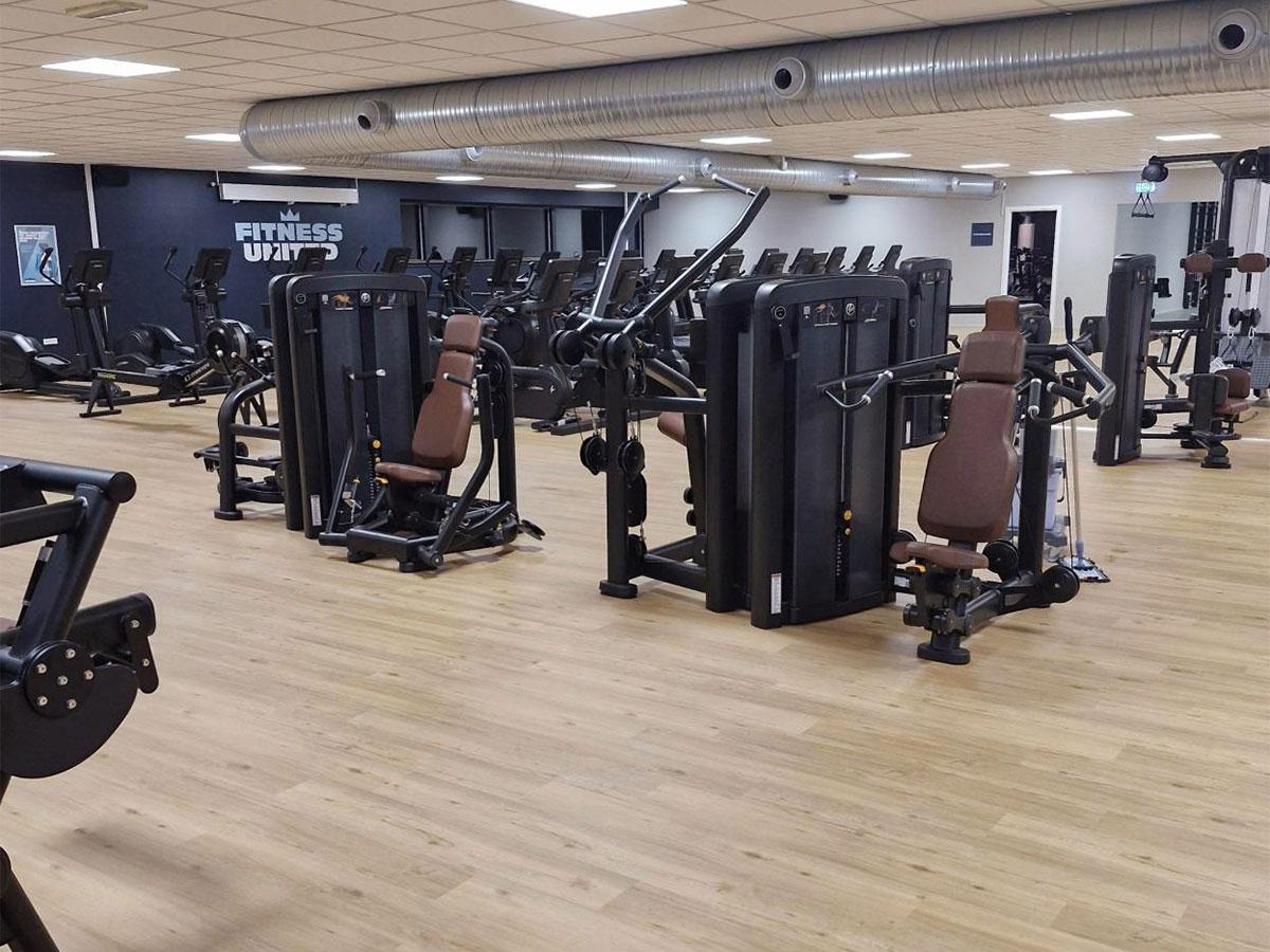 Bilde av nytt gulv i et treningssenter, med treningsapparater i bakgrunnen