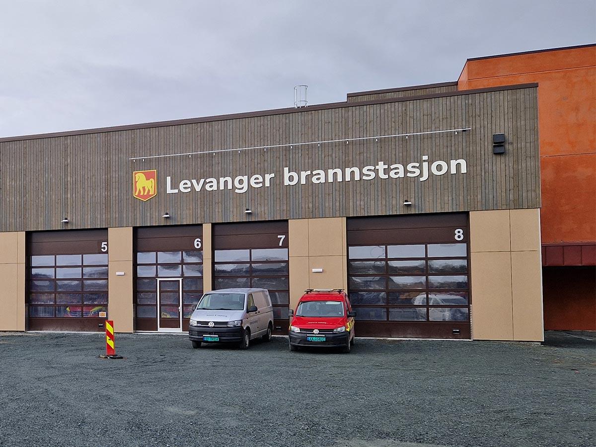 Fasaden til Levanger Brannstasjon. To biler står foran en av portene.