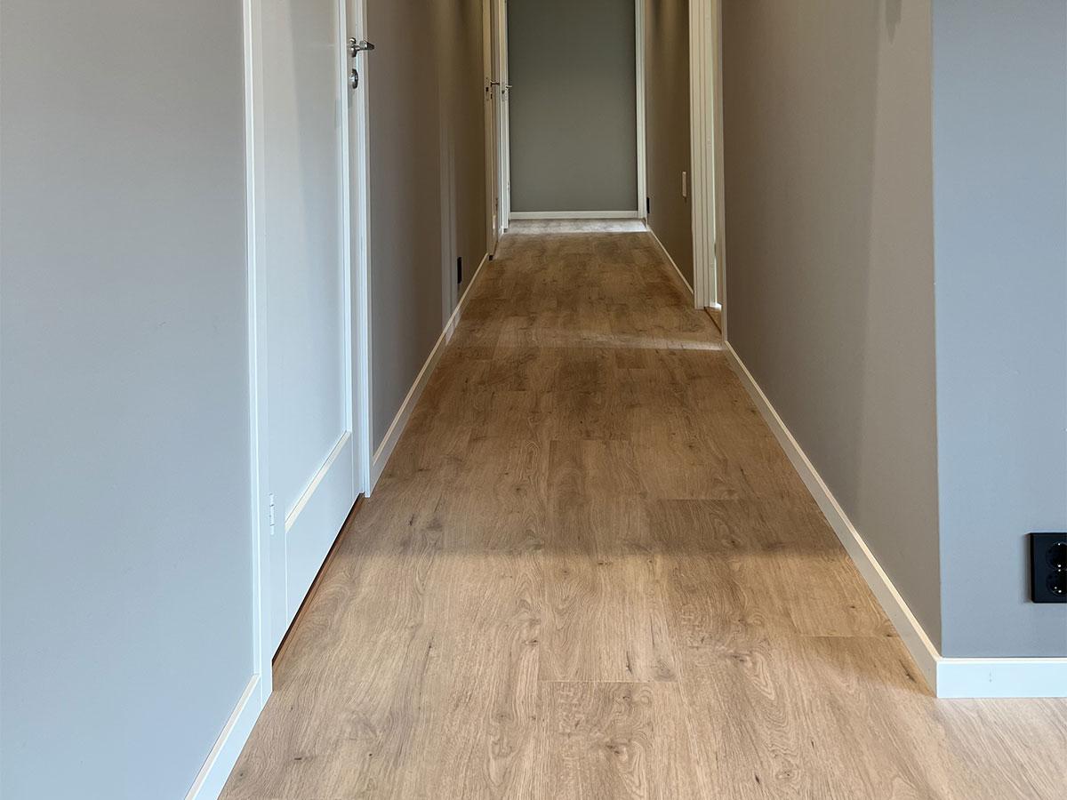 Gangen i et nybygget hus med nytt gulv, uten møbler 