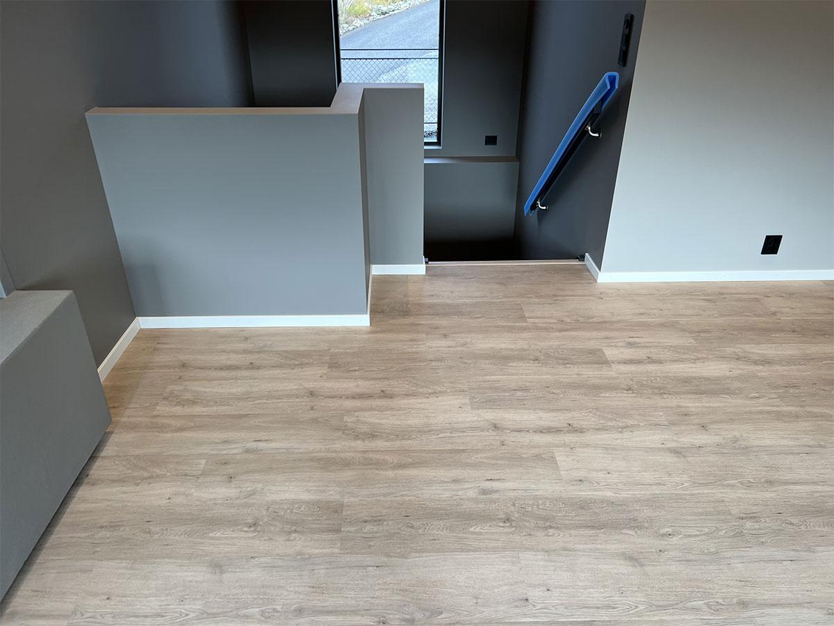 Stue  og trapp ned i et nybygget hus med nytt gulv, uten møbler 