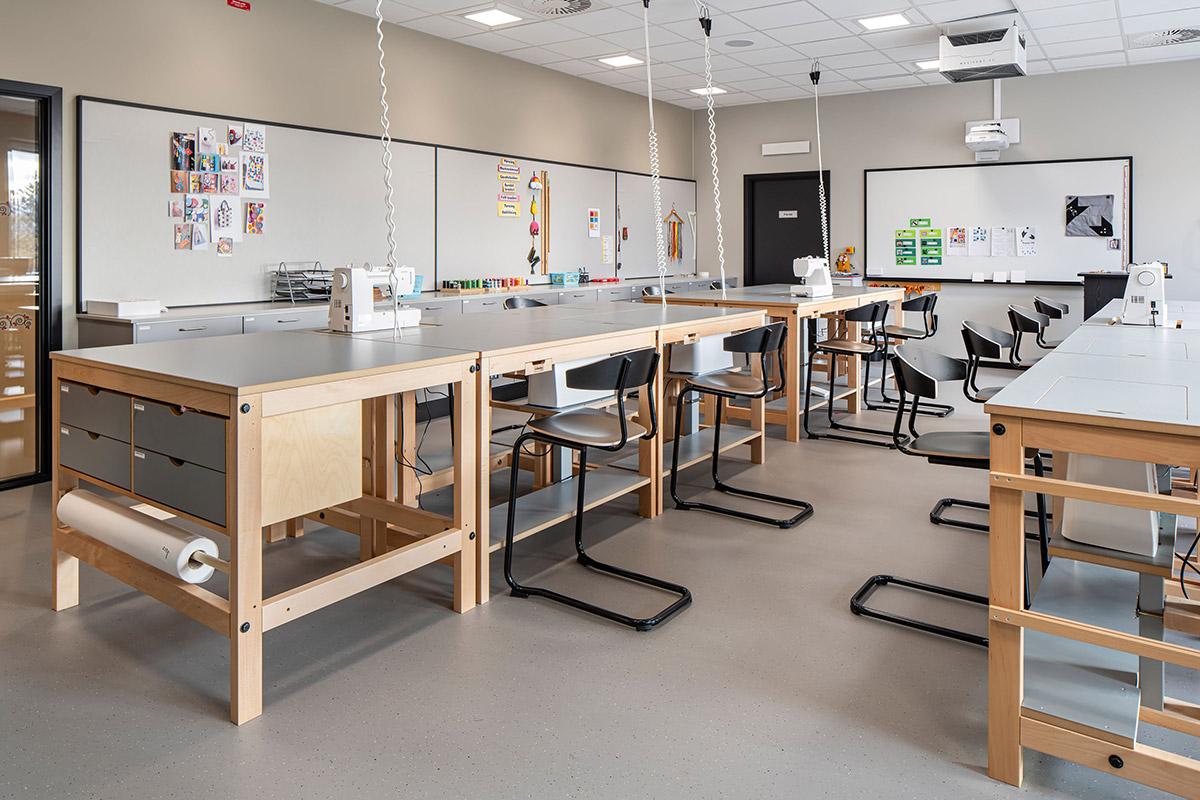 klasserom på skolen med arbeidsbenker og stoler. Symaskin stående oppå arbeidsbenken