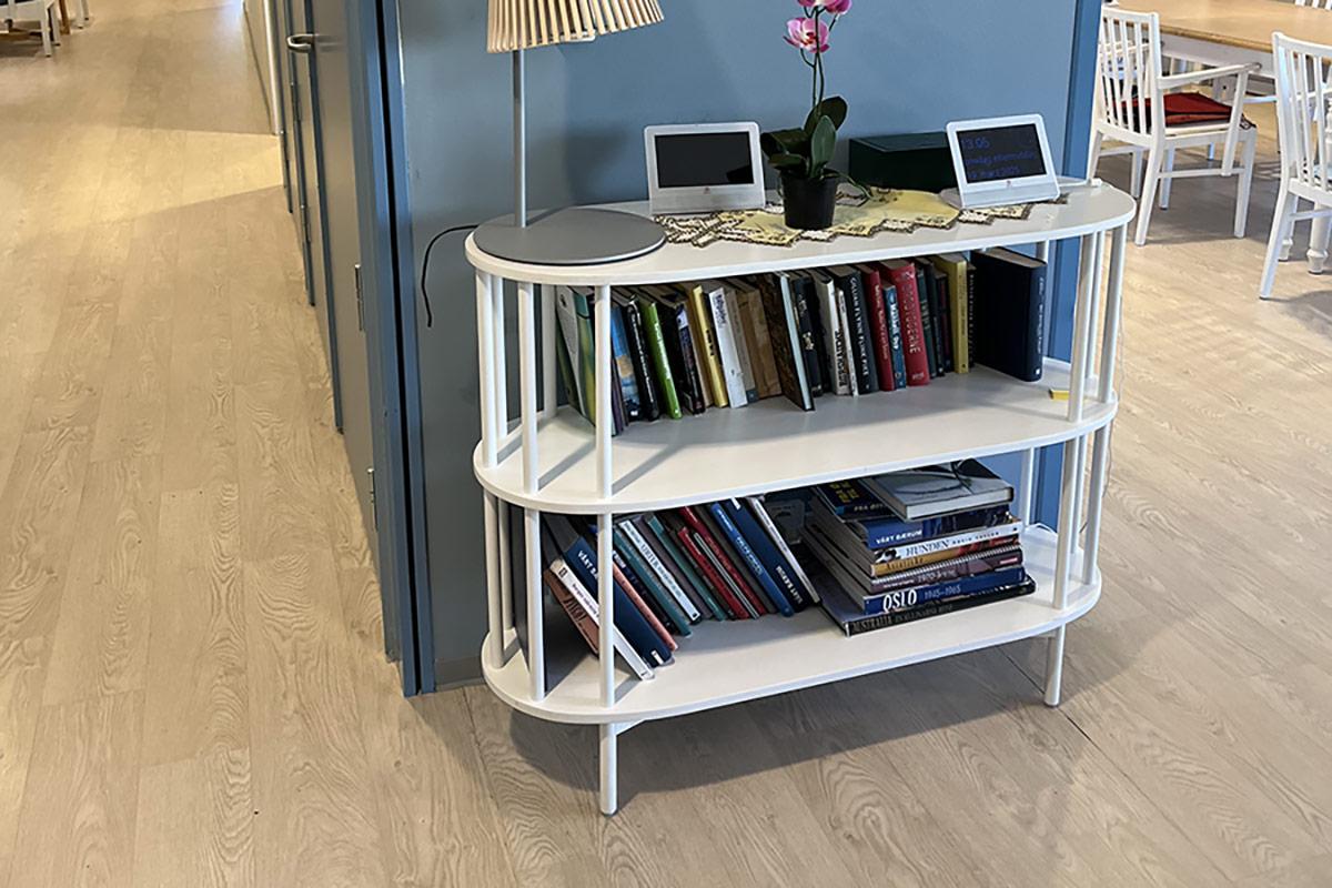 kort vegg malt i blått med en liten hylle og lampe foran. Til høyre kan man se inn på kjøkkenet og til venstre kan man se innover i gangen