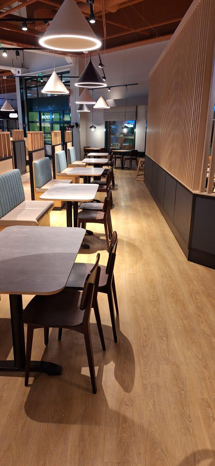 Små spisegrupper i en kafeteria i Finland. Til høyre, en spilevegg