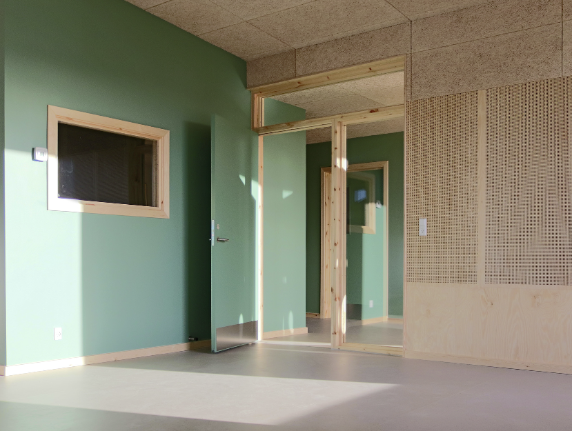 et lyst rom i en barnehage med grønne vegger og lyst gulv