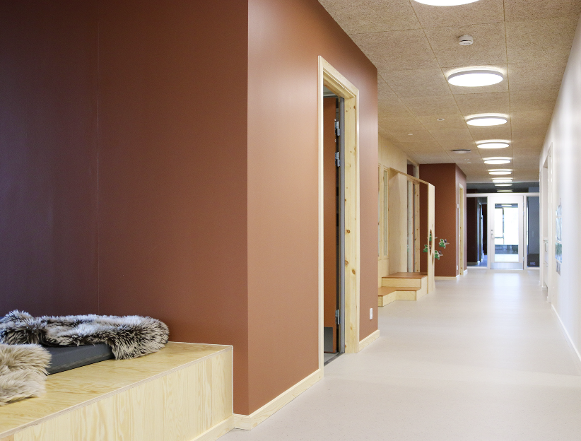 en gang i en barnehage med brune vegger og lyst gulv