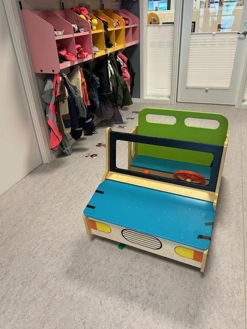 en lekebil i sterke farger stående på gulvet i gangen i en barnehage