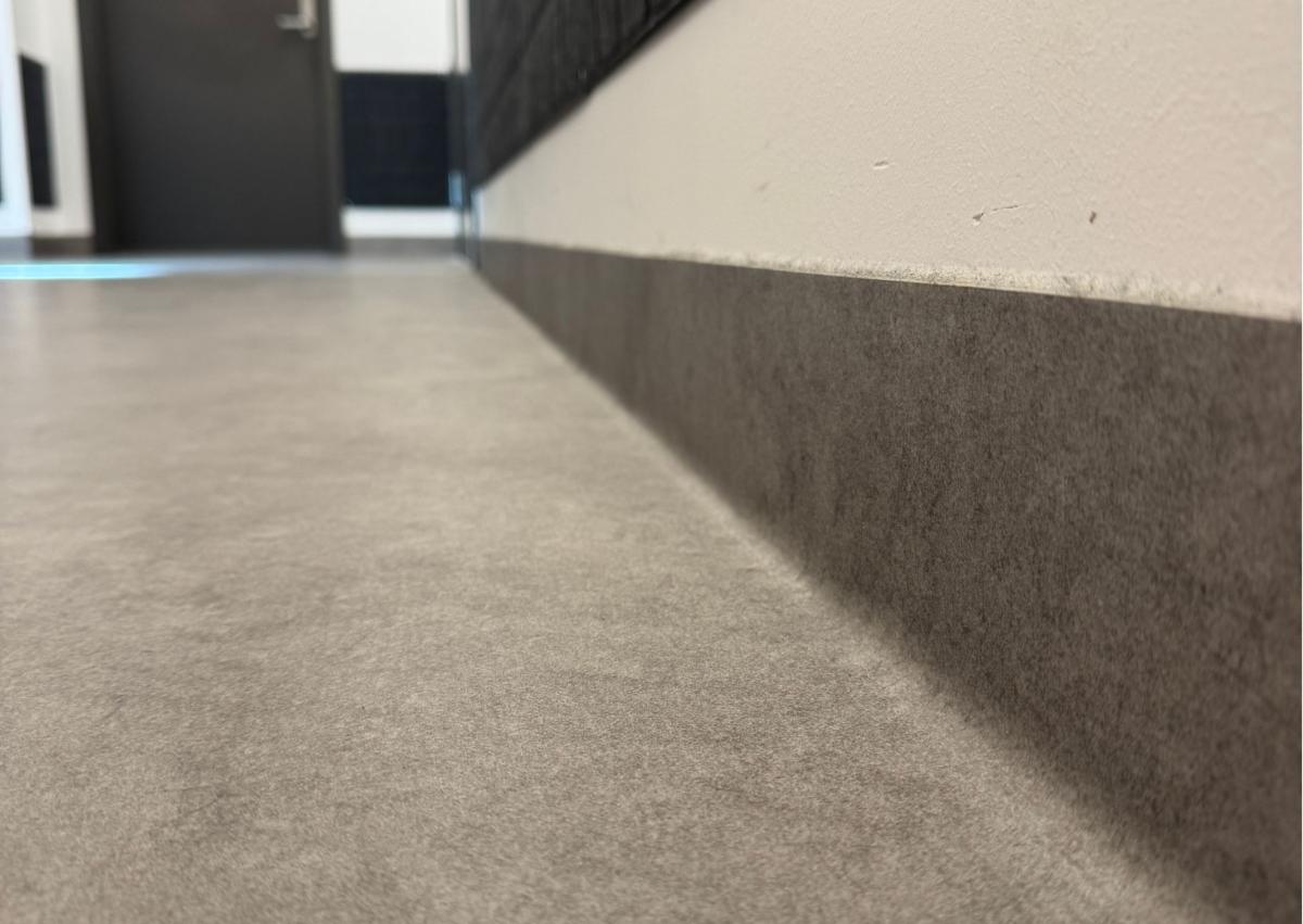 nærbilde av overgangen mellom gulv og vegg. Gulvet former en list noen cm opp på veggen