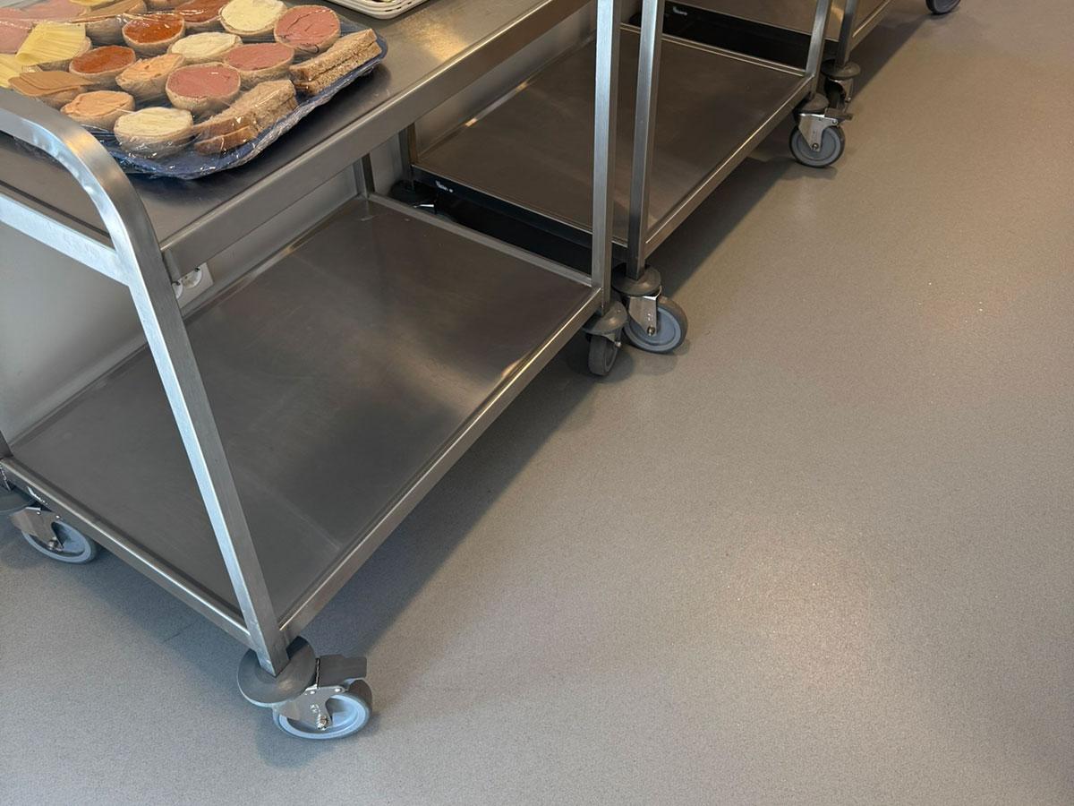 rullebord i metall med mat på et grått gulv