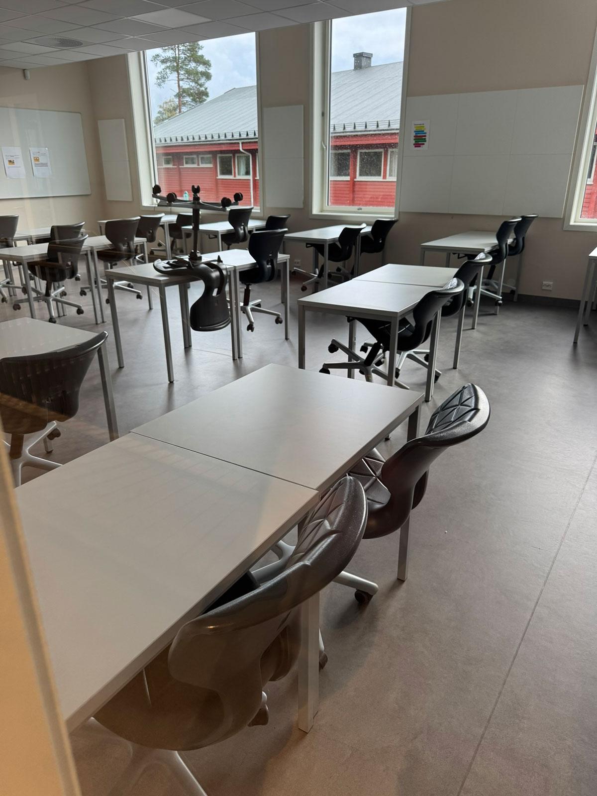 Et tomt klasserom med hvite pulter og sorte stoler