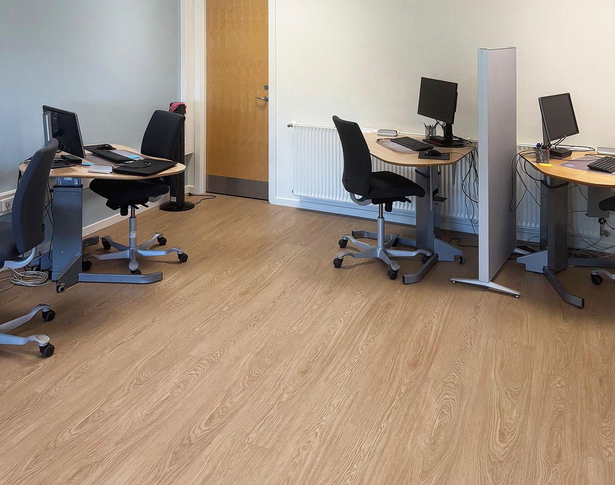 fire skrivepulter med stoler stående langs veggene i et kontor