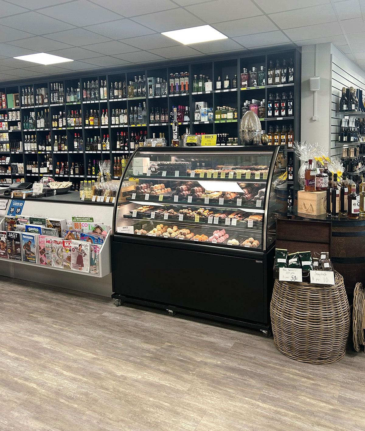 disken i en butikk som selger vin og alkohol. Ved siden av disken ser man et glassmonter med makroner og andre søtsaker