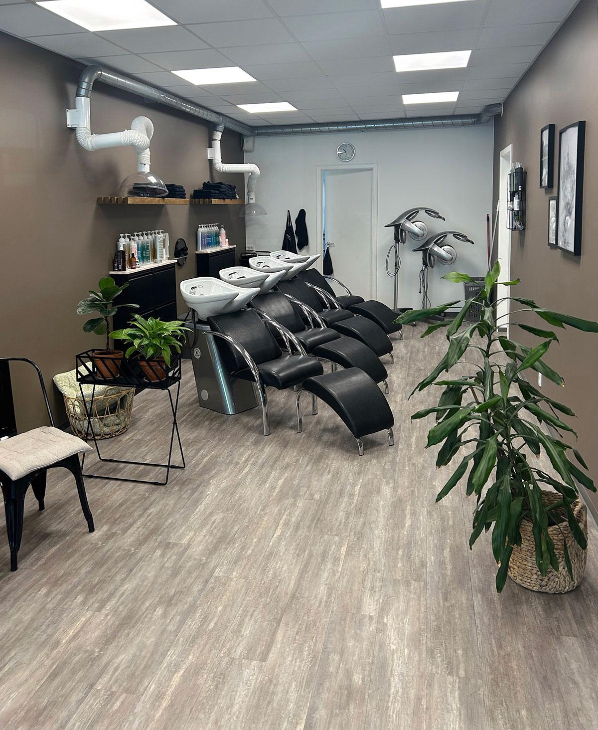 tre stoler for hårvask i en frisørsalong stående skrått på rad innover i bildet.