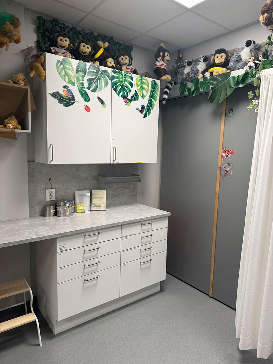 skap og benk i et behandlingsrom. barnevennlig dekor på skap og høyt oppe på veggen