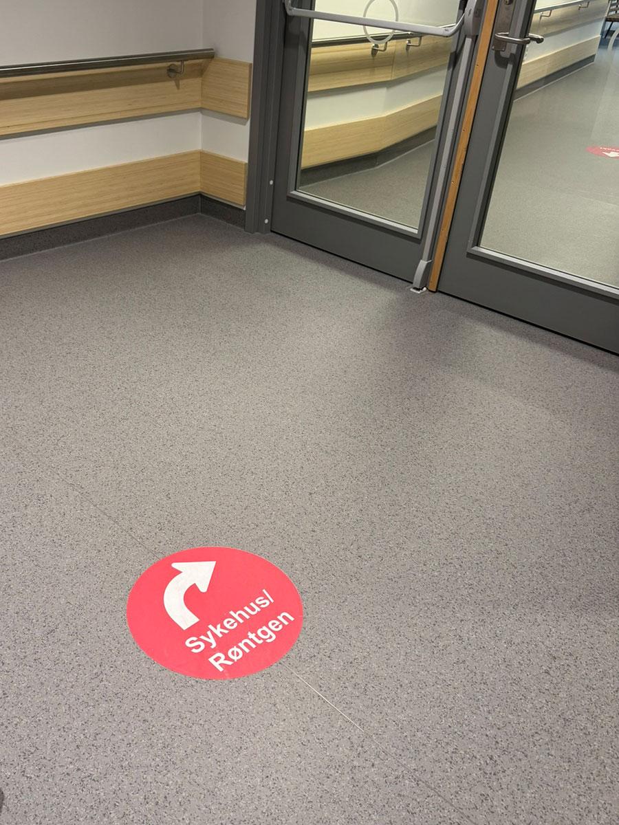 gulv med et rødt foliemerke med pil som viser vei til sykehus/røntgen