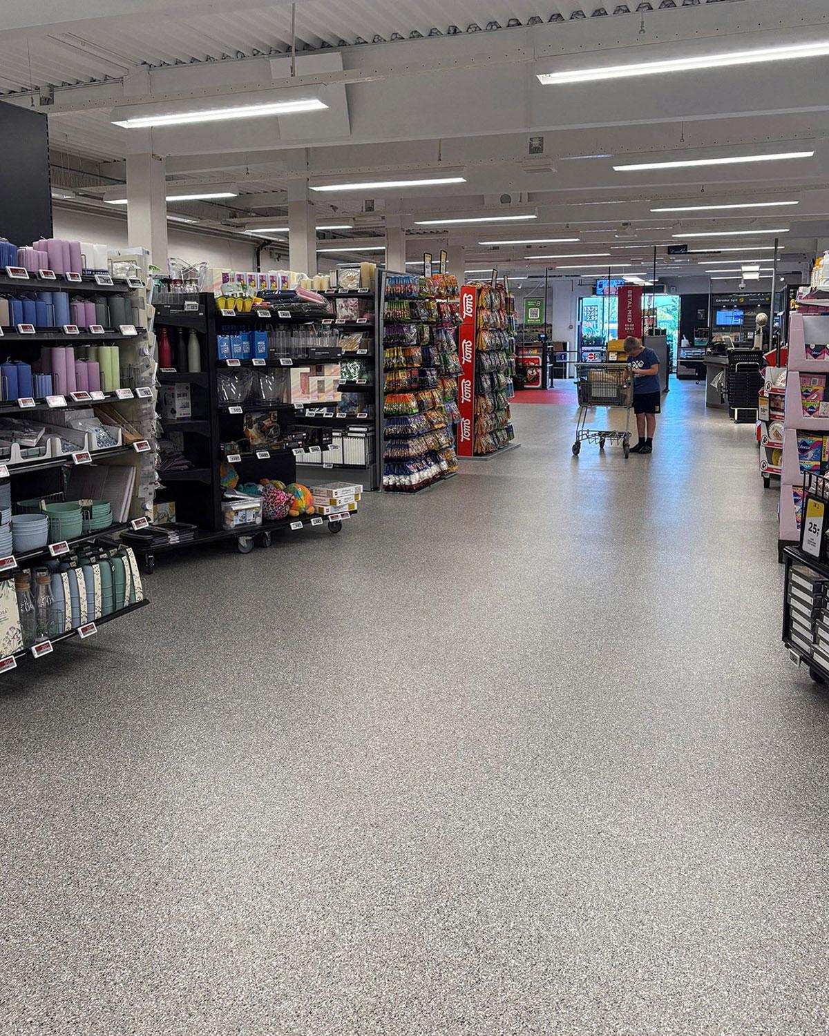 butikk med grått gulv og mange hyller på venstre side