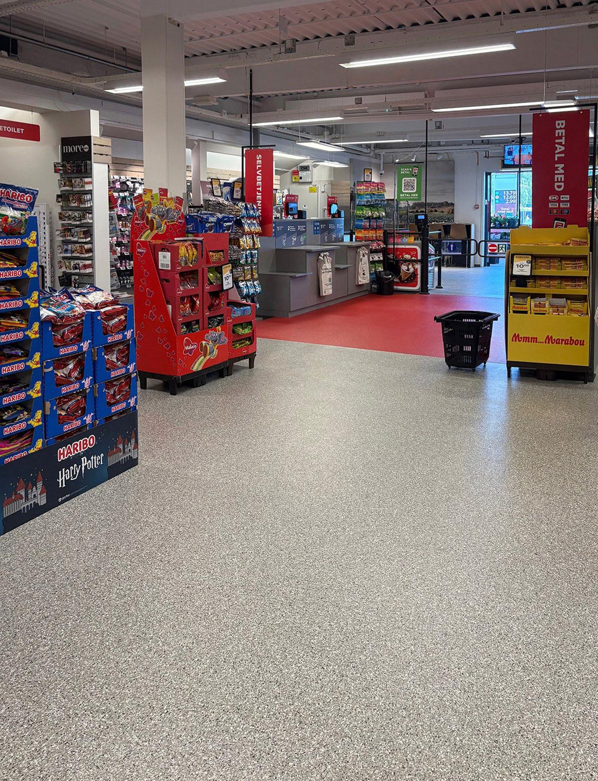 kasseområde i en matbutikk med selvbetjente kasser og rødt gulv som markerer sonen for kassen