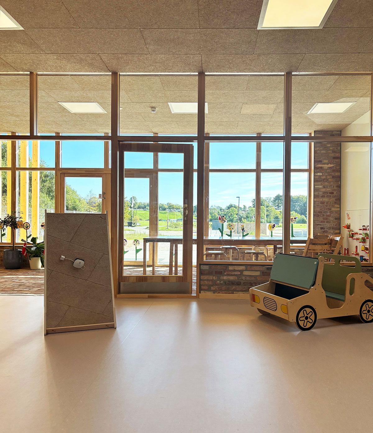 en lekebil og et sepil stående på gulvet foran døren inn til et oppholdsrom på et barnehjem