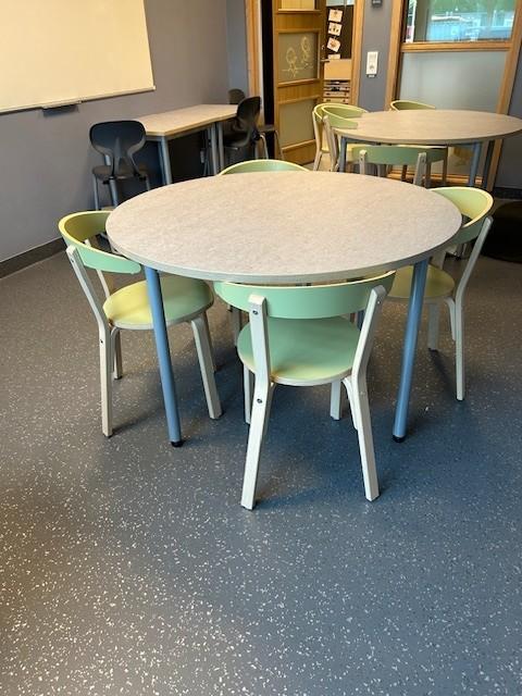 et klasserom på en skole med runde bord og stoler.