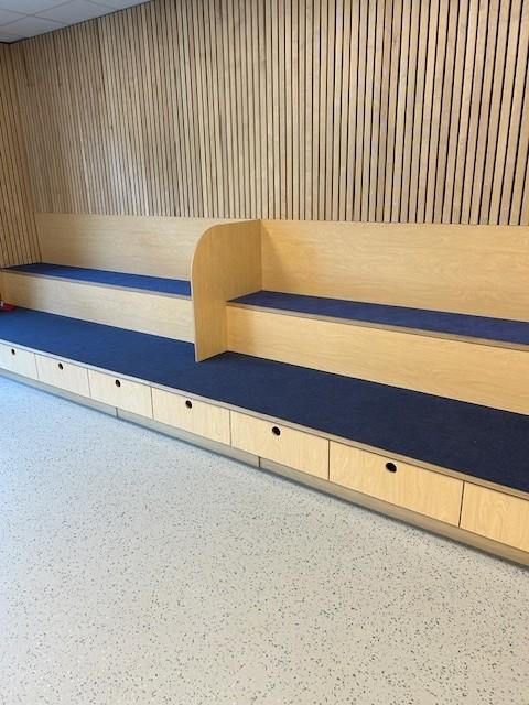 en benk med to nivåer stående langs en vegg. Benken har blå puter