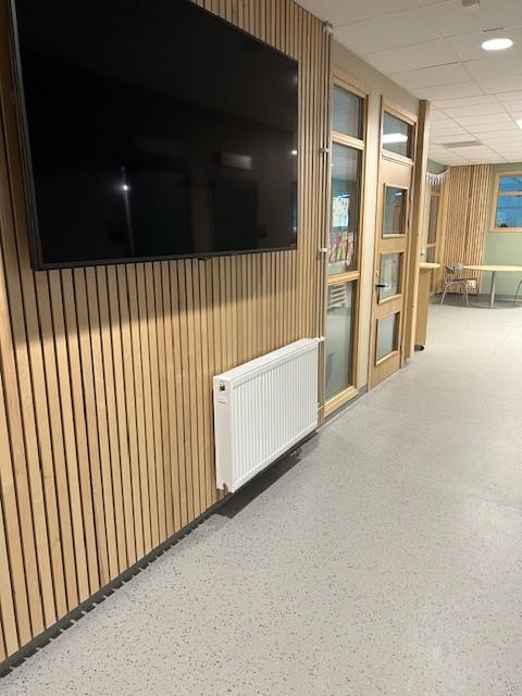 en tv hengende på en vegg i en gang på en skole