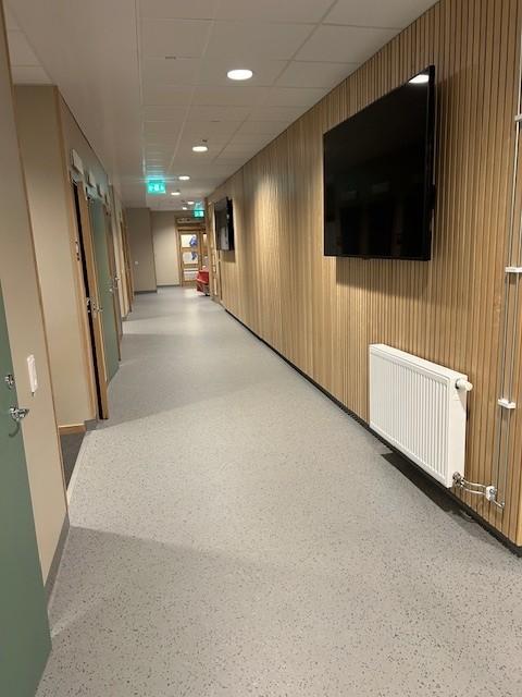 gangen på en skole med lyse vegger og en tv hengende på veggen til høyre