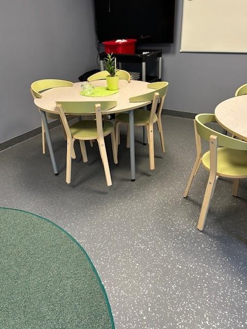 et klasserom på en skole med runde bord og stoler.