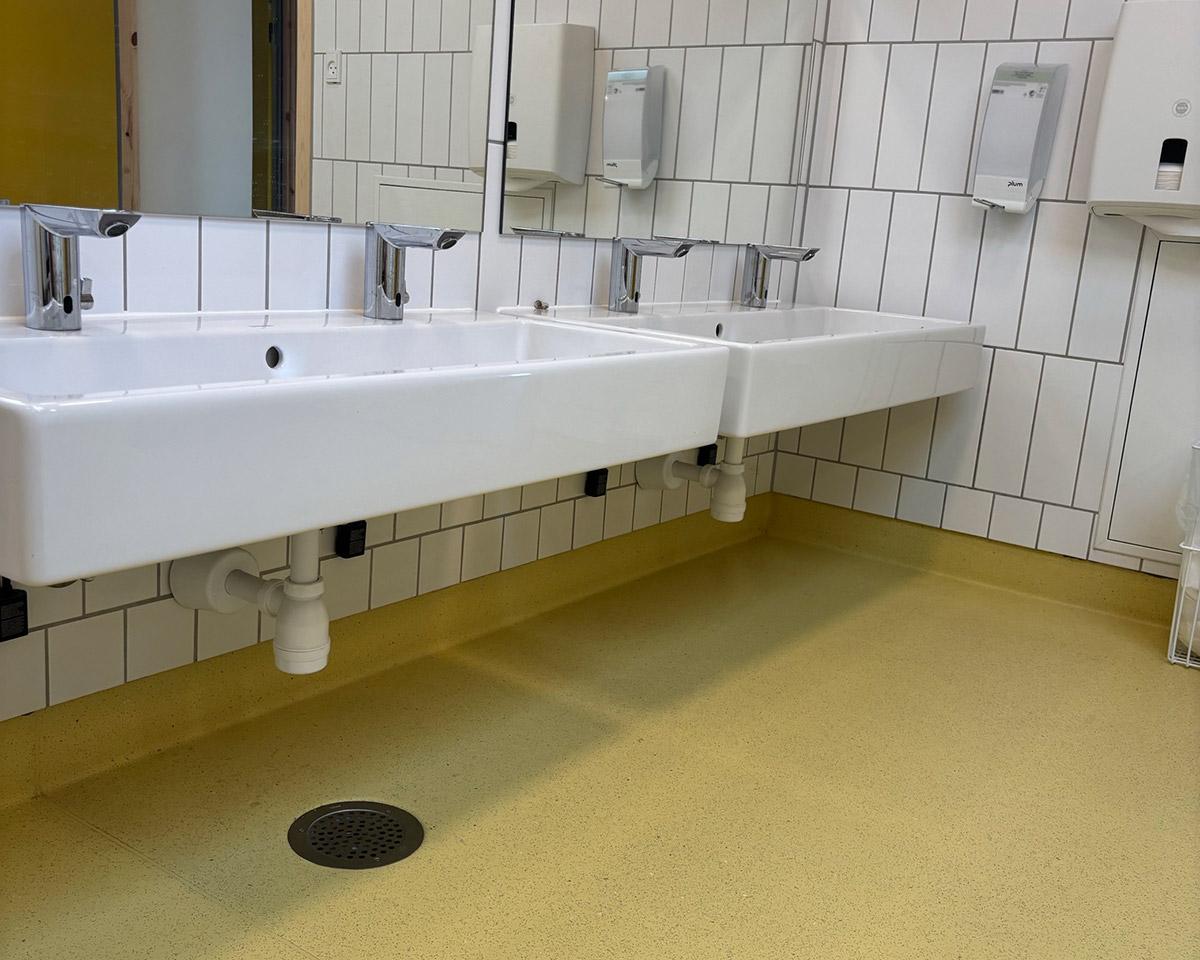 en rekke med vaskeservanter på et wc med gult gulv