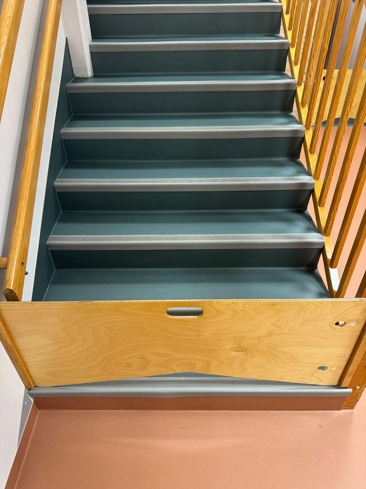 trapp opp med blå trinn og en kort vegg på nederste trinn for å hindre barn i å gå i trappen