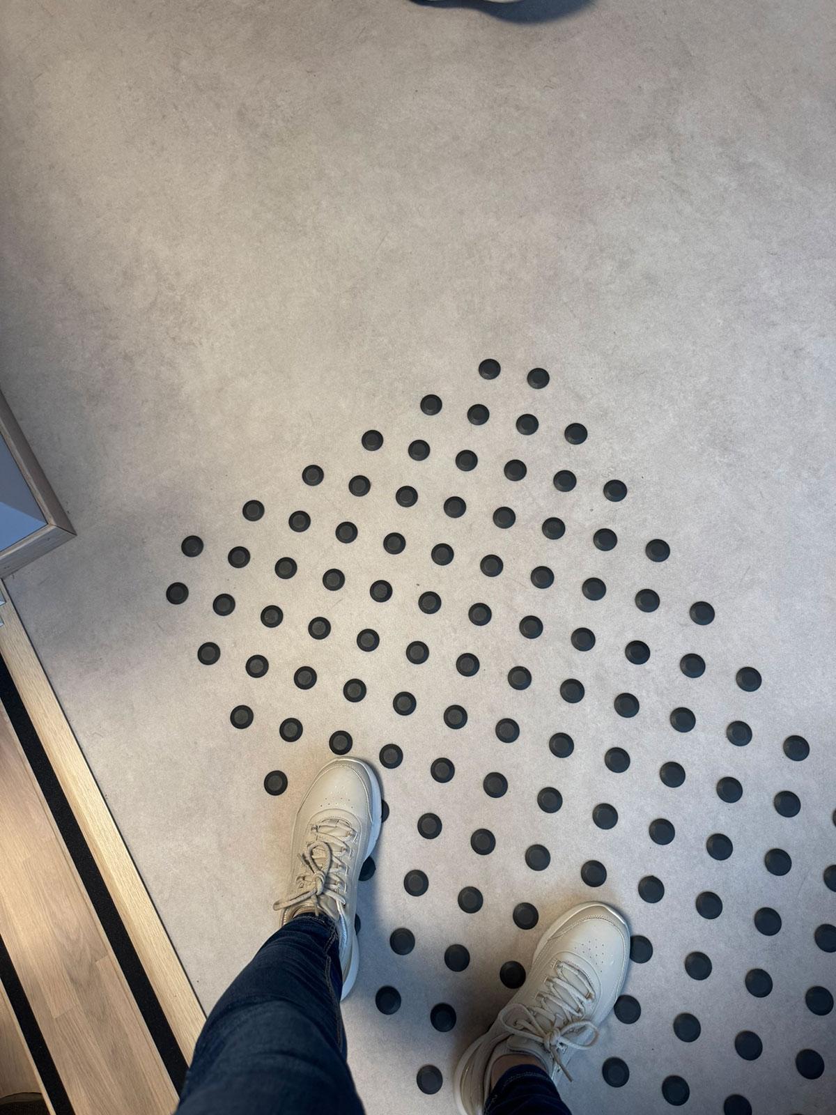 nærbilde av opphøyde sorte knotter på et gulv for å sklisikre område. to føtter i nederste del av bildet står på knottene