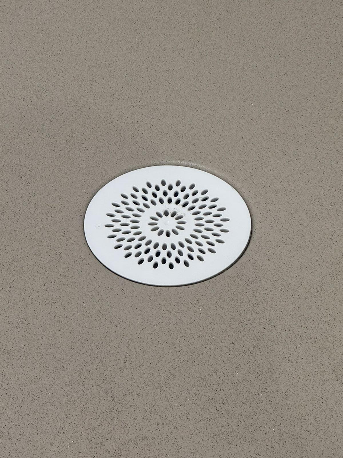 nærbilde av et sluk i hvit på et grått gulv