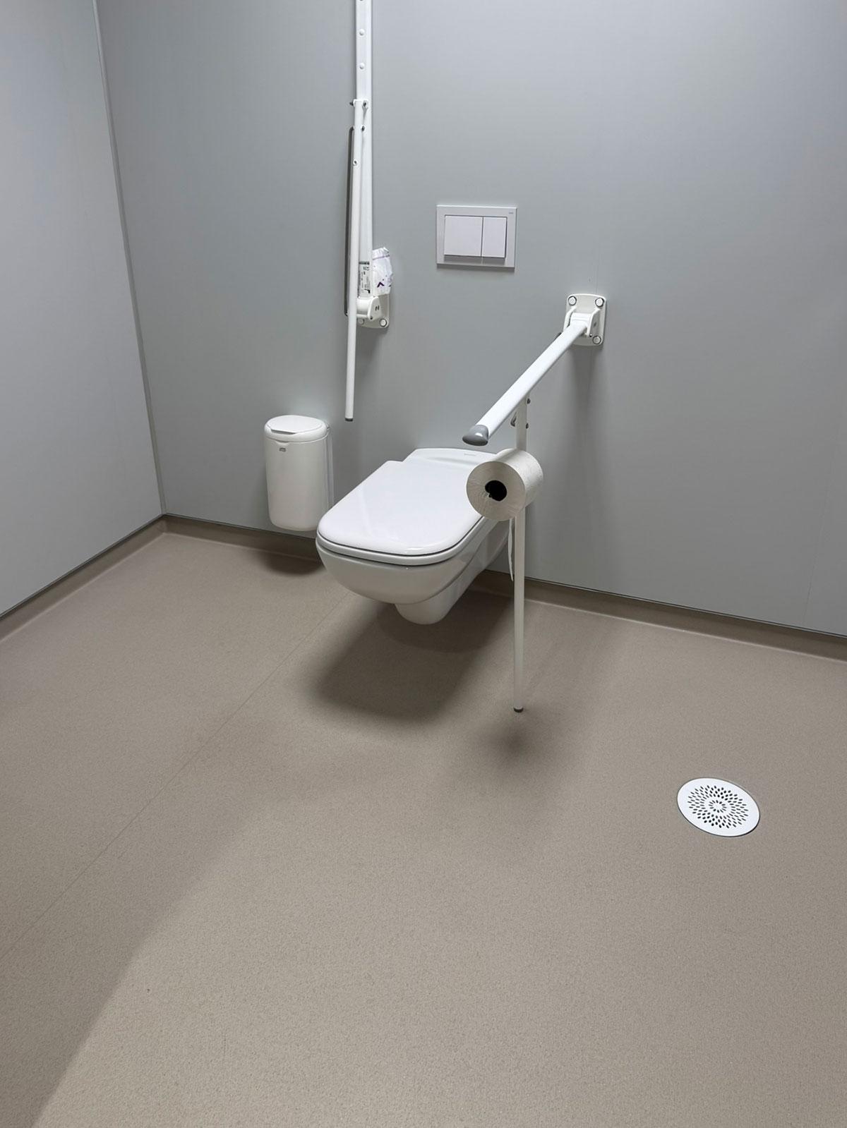 toalett hengende på en grå vegg med stolper ut fra veggen