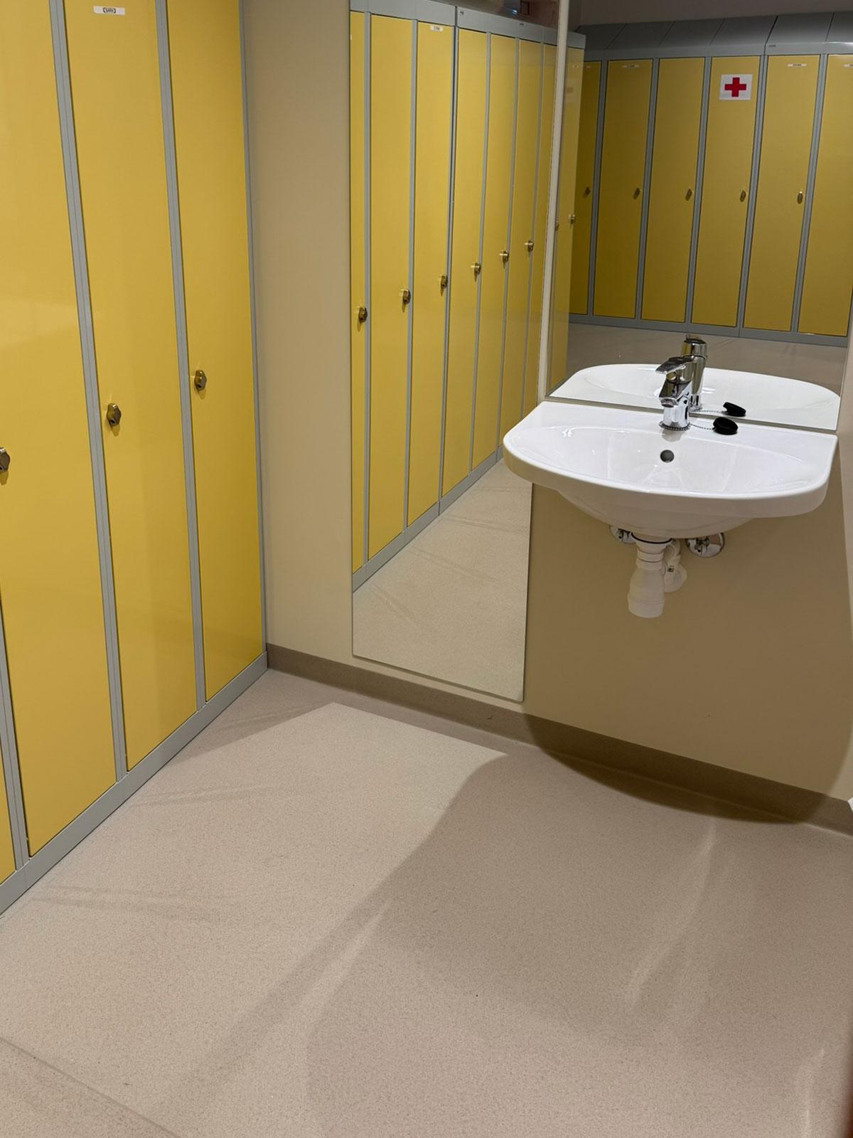 garderobe med vaske servant foran speilet og garderobeskap med gule fornter til venstre